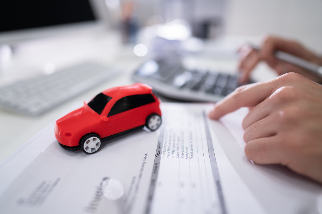 Red Car In Front Of Businessman Calculating Loan In Office